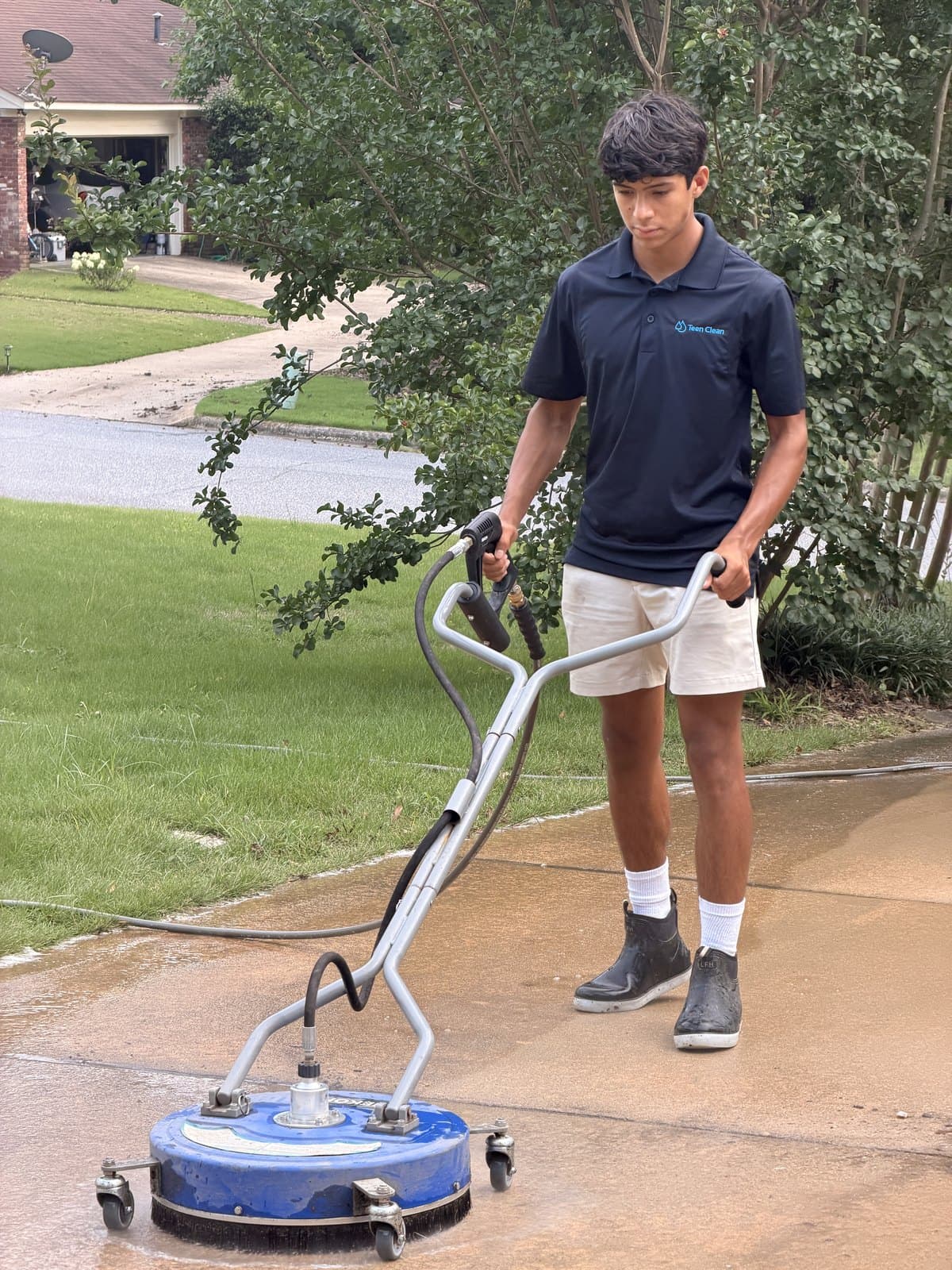 Team Clean technician using a surface cleaner to pressure wash a concrete driveway in the Columbus, GA area