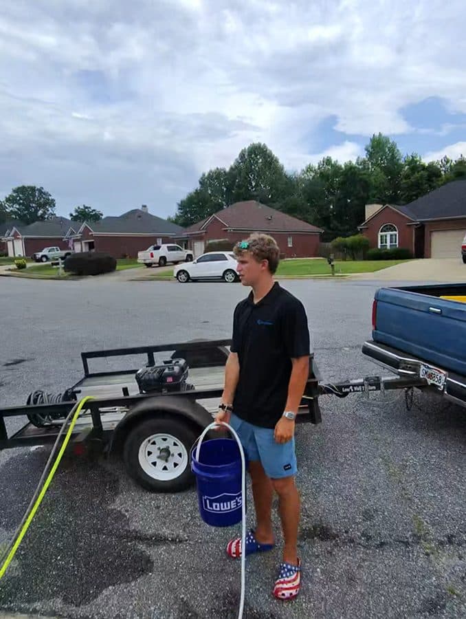 Team Clean team member standing near pressure washing equipment and trailer